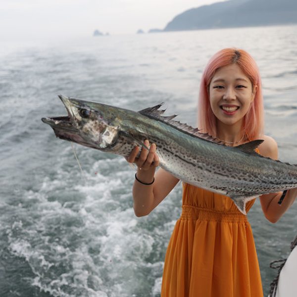 拿著在遊艇上釣到的魚的遊客